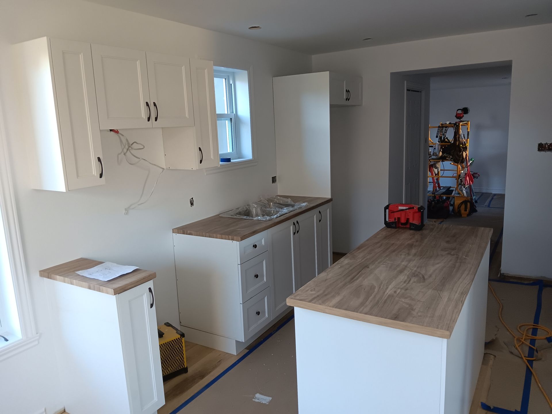 Une cuisine en construction avec des armoires blanches et un comptoir en bois.
