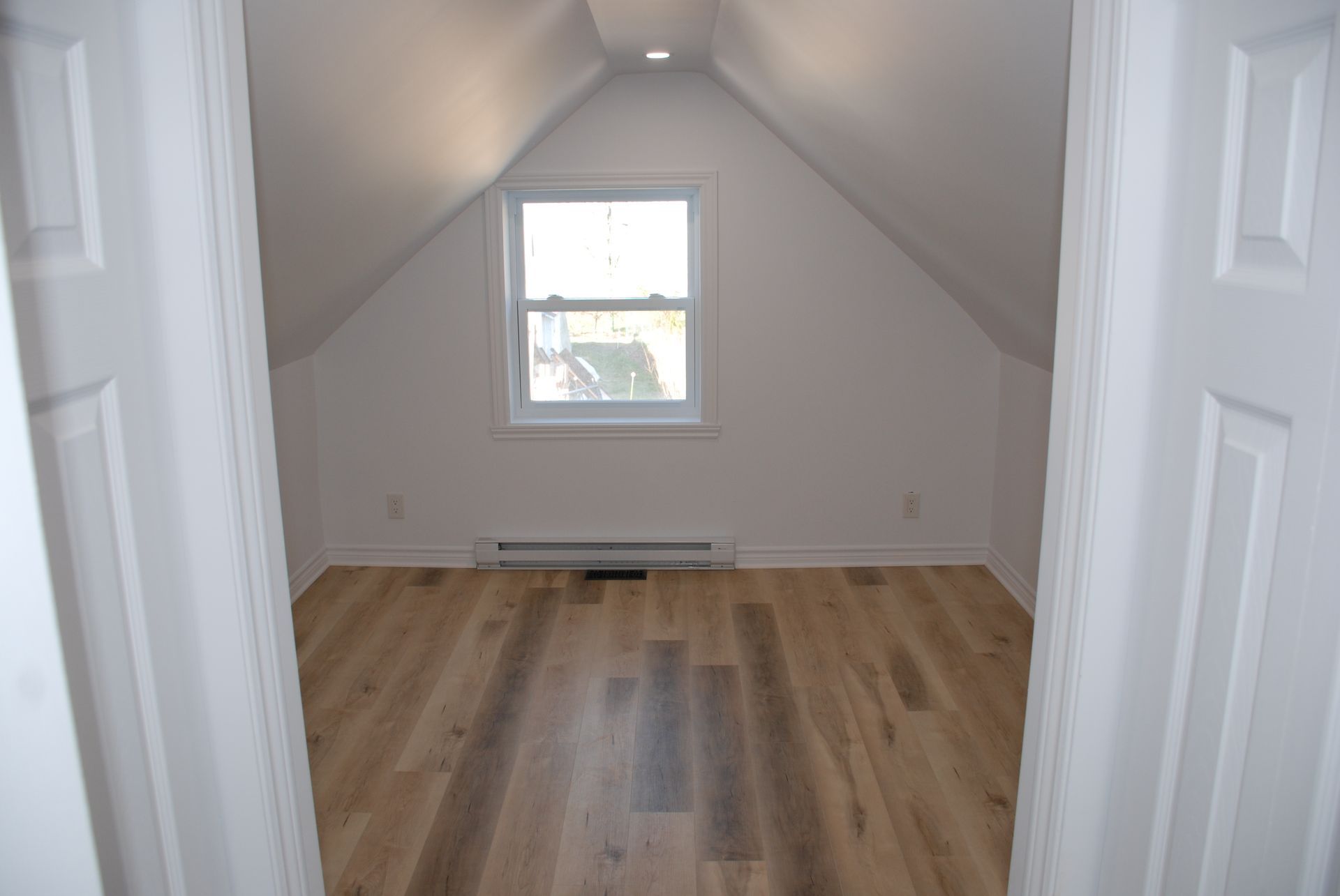 Une pièce vide avec du parquet et une fenêtre.