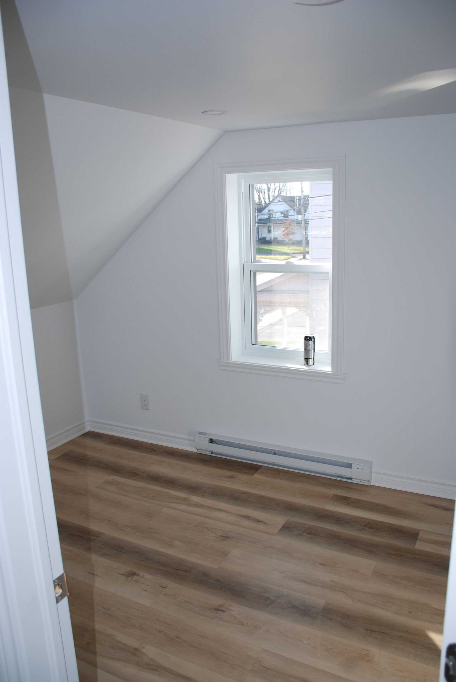 Une pièce vide avec du parquet et une fenêtre