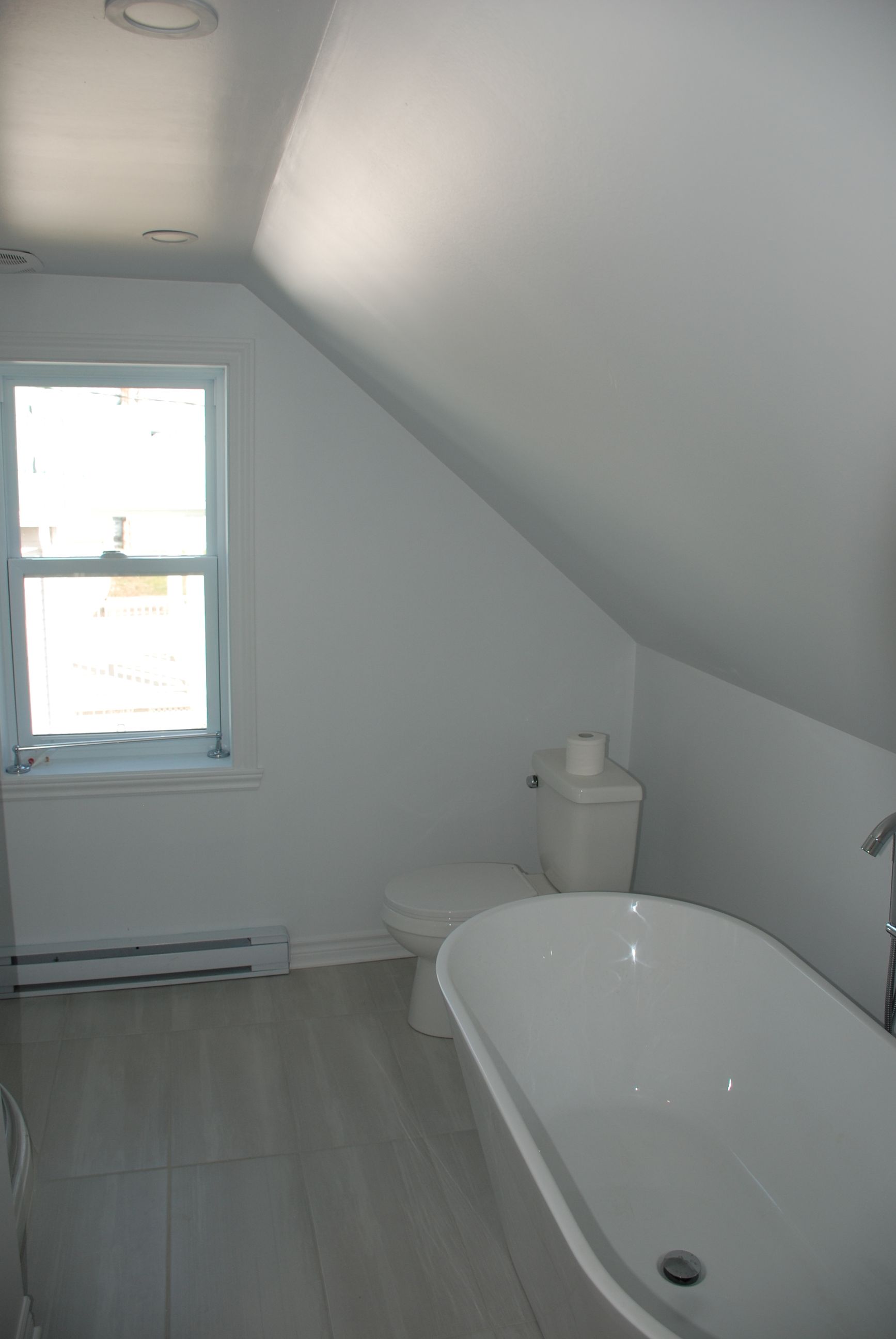 Une salle de bain avec baignoire , toilettes et fenêtre.