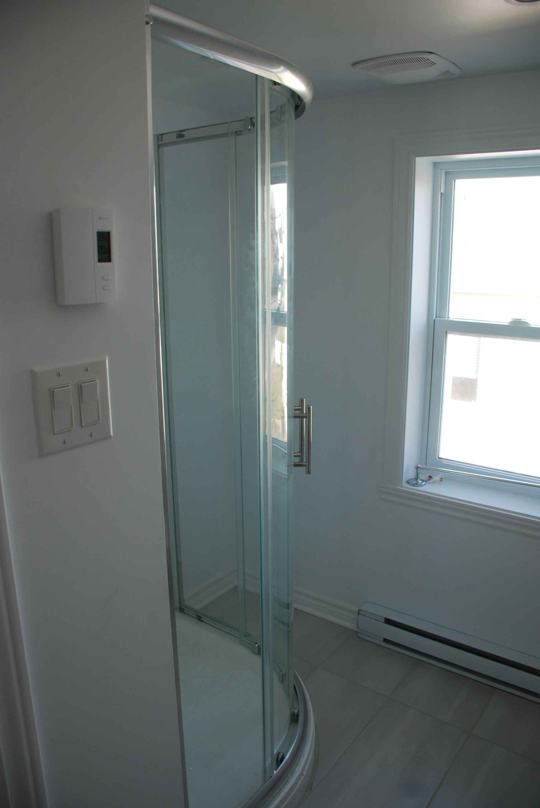 Une salle de bain avec cabine de douche et fenêtre.
