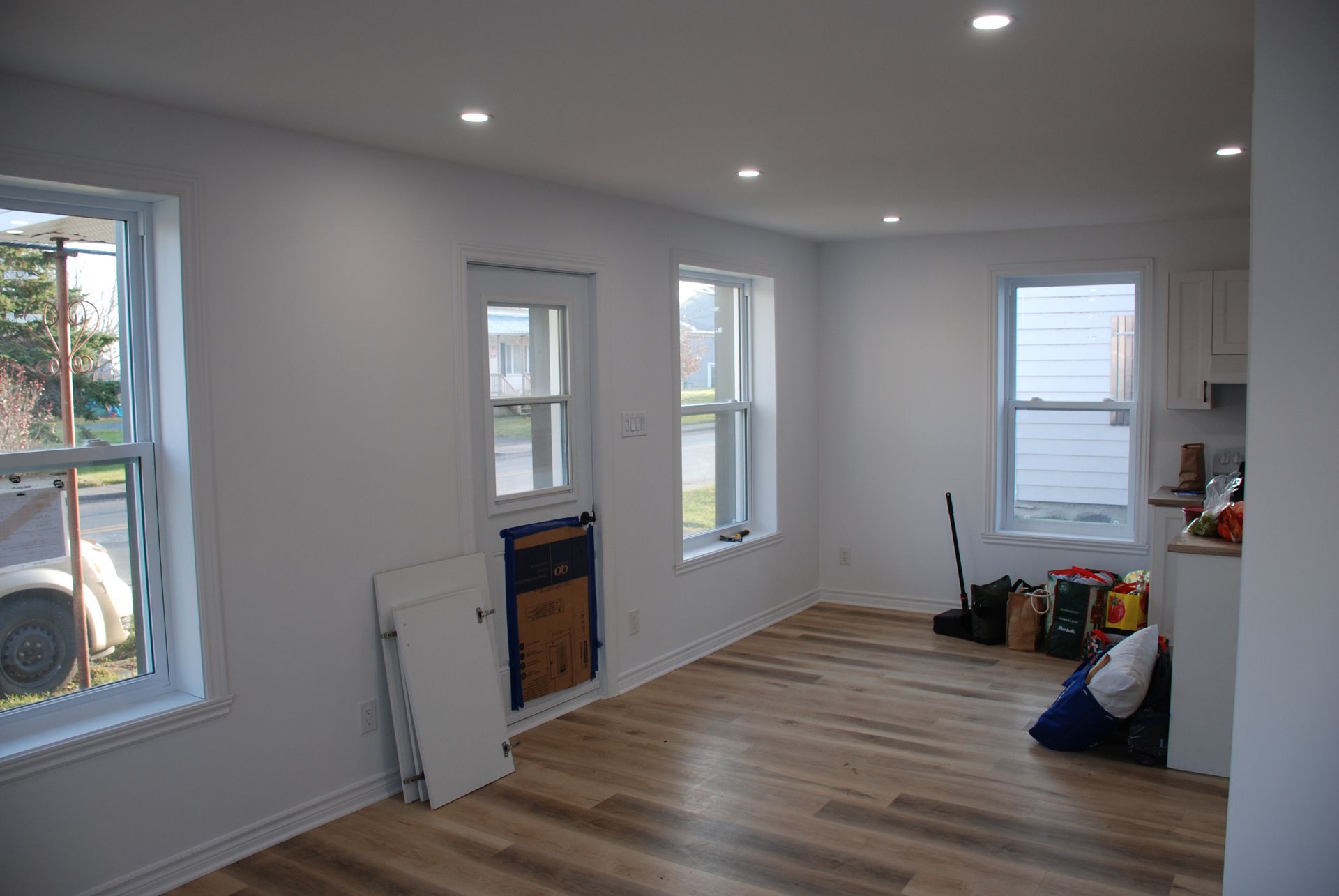 Un salon vide avec parquet et murs blancs.