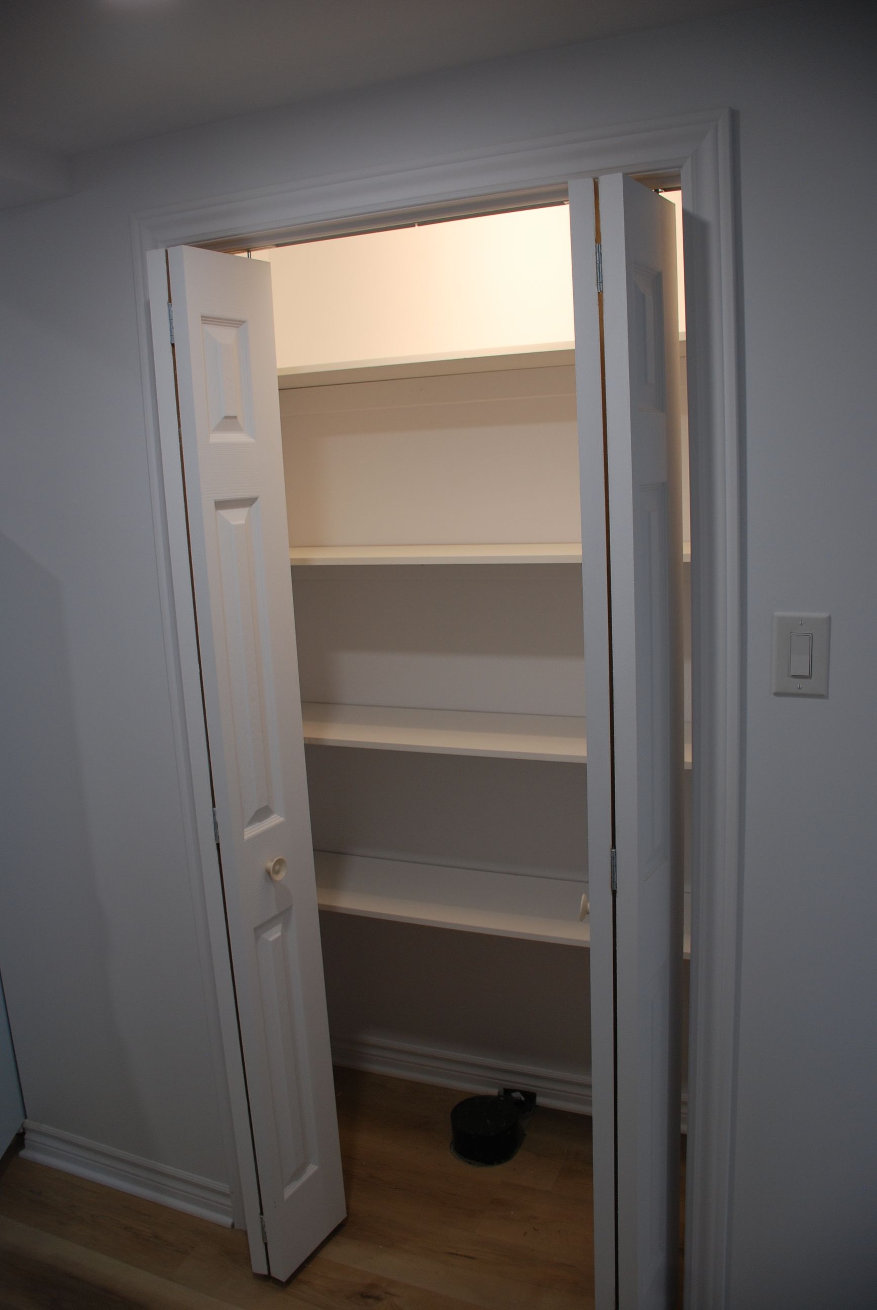 Un placard avec étagères et une porte ouverte