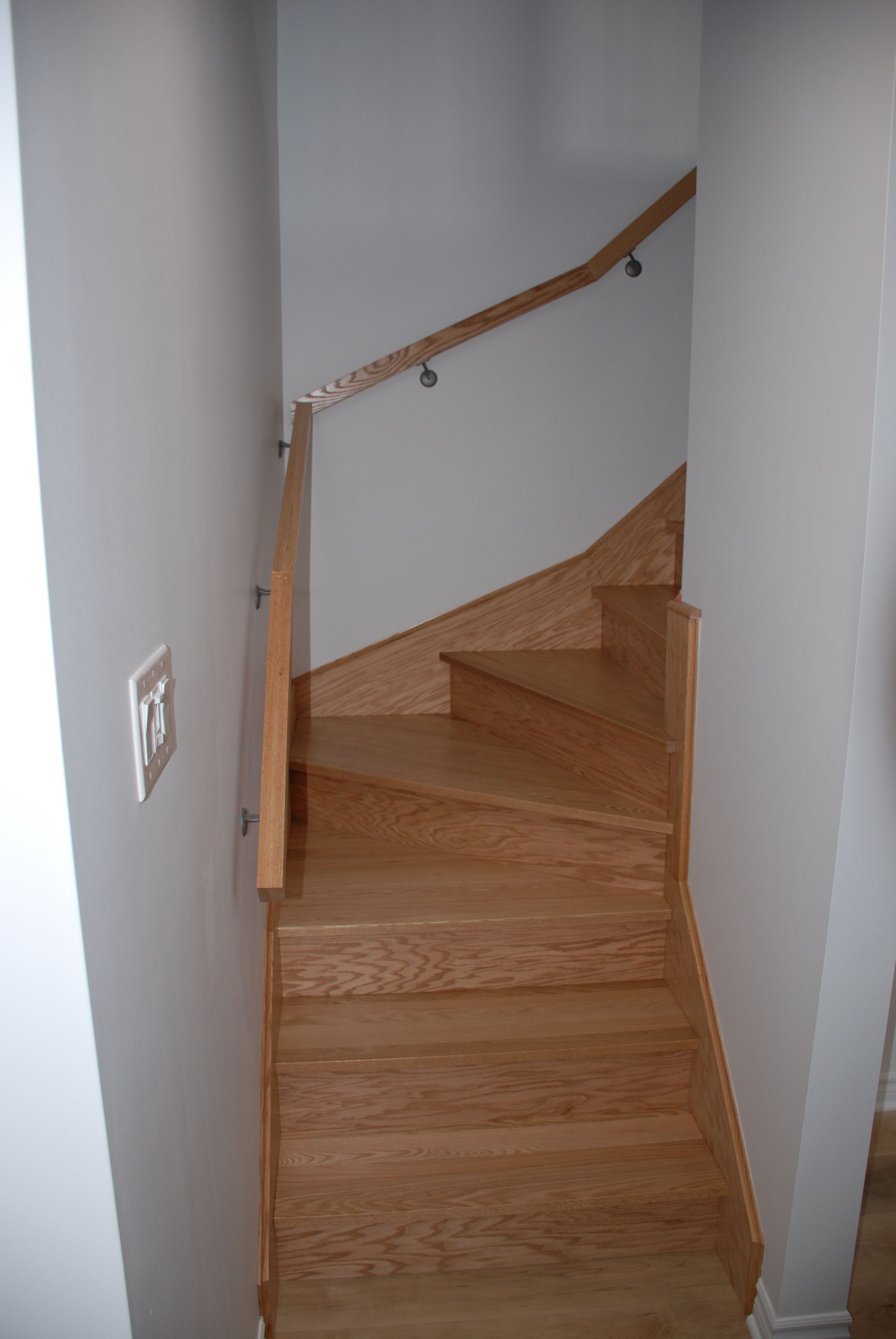 Un escalier en colimaçon en bois avec une rampe blanche