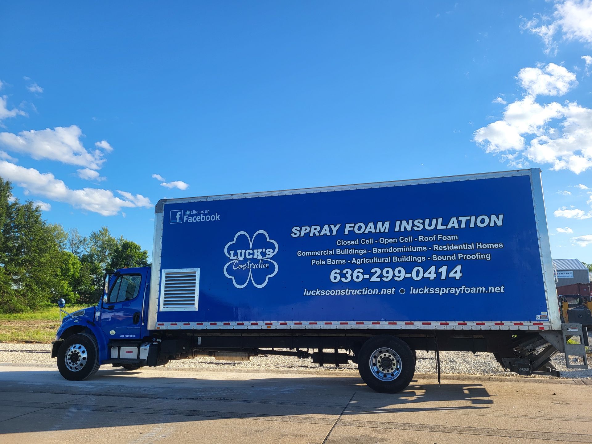 A blue truck that says spray foam insulation is parked on the side of the road