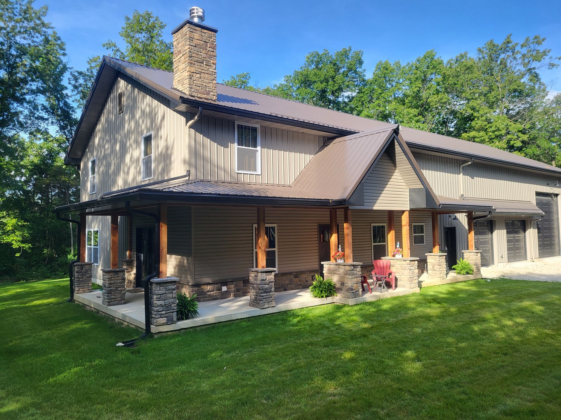 A large house with a porch and a garage is sitting on top of a lush green field.