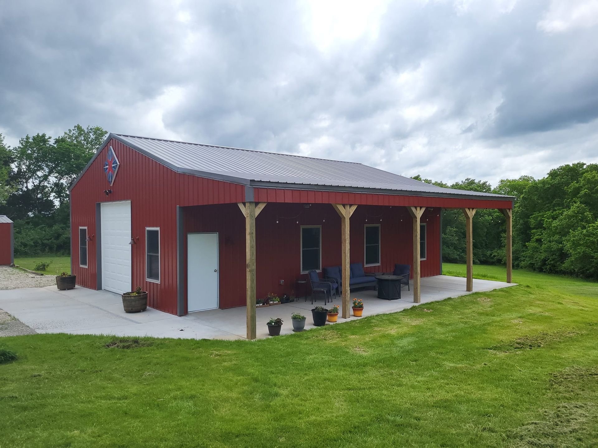 A red barn with a porch in the middle of a grassy field.