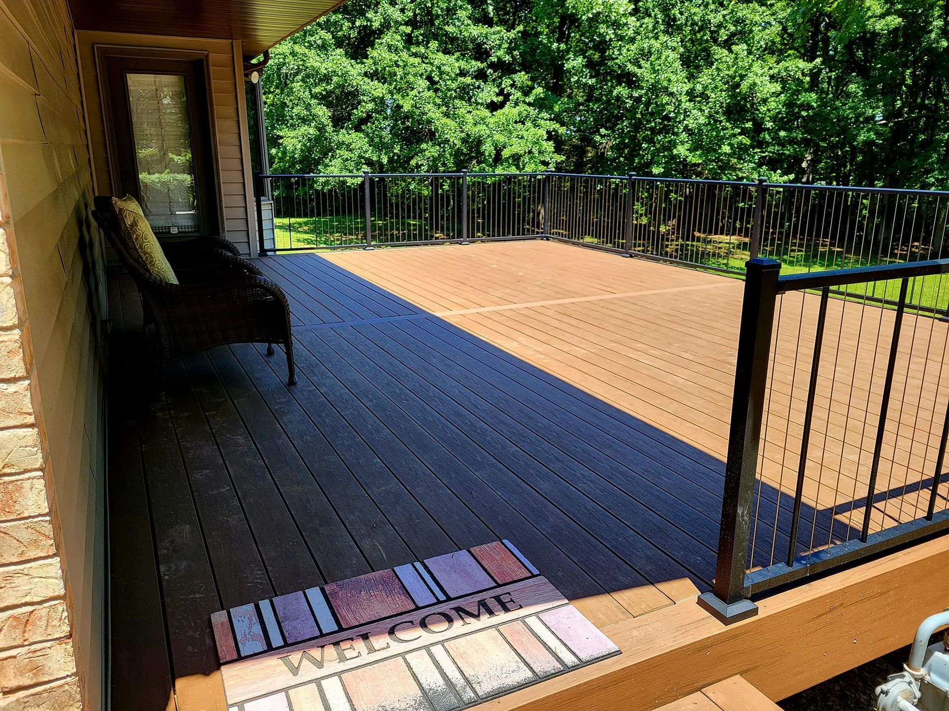 A wooden deck with a welcome mat on it