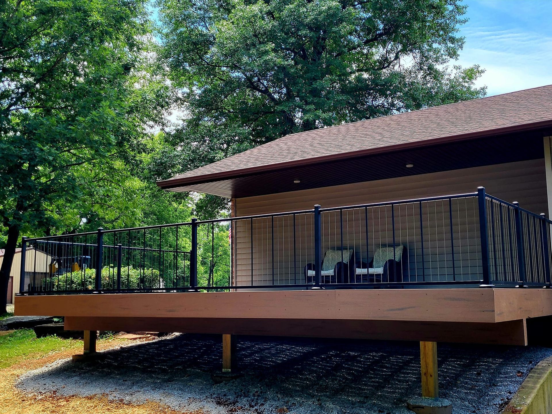 A small house with a large deck in front of it surrounded by trees.