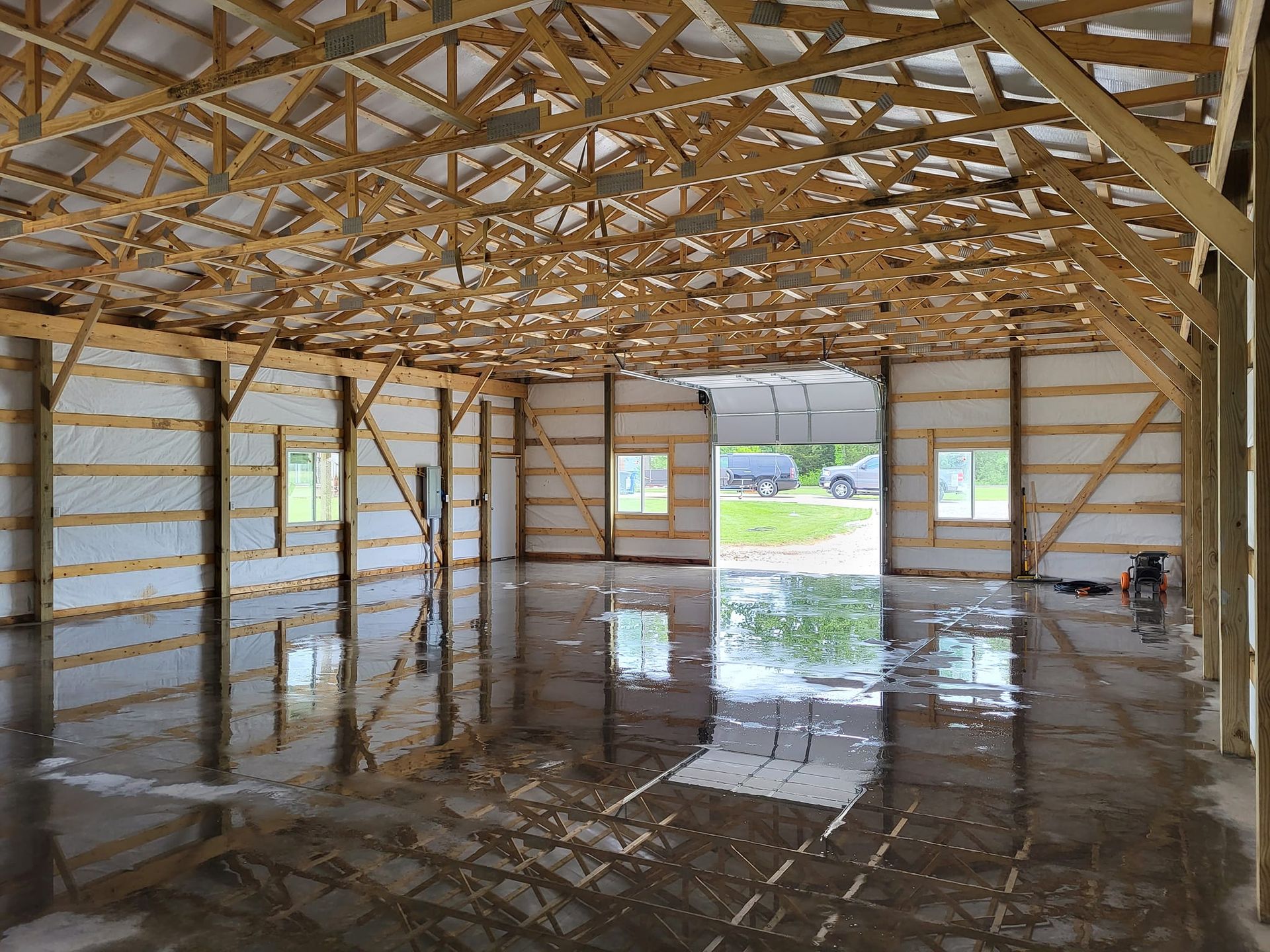 A large empty building with a wooden roof and a concrete floor.