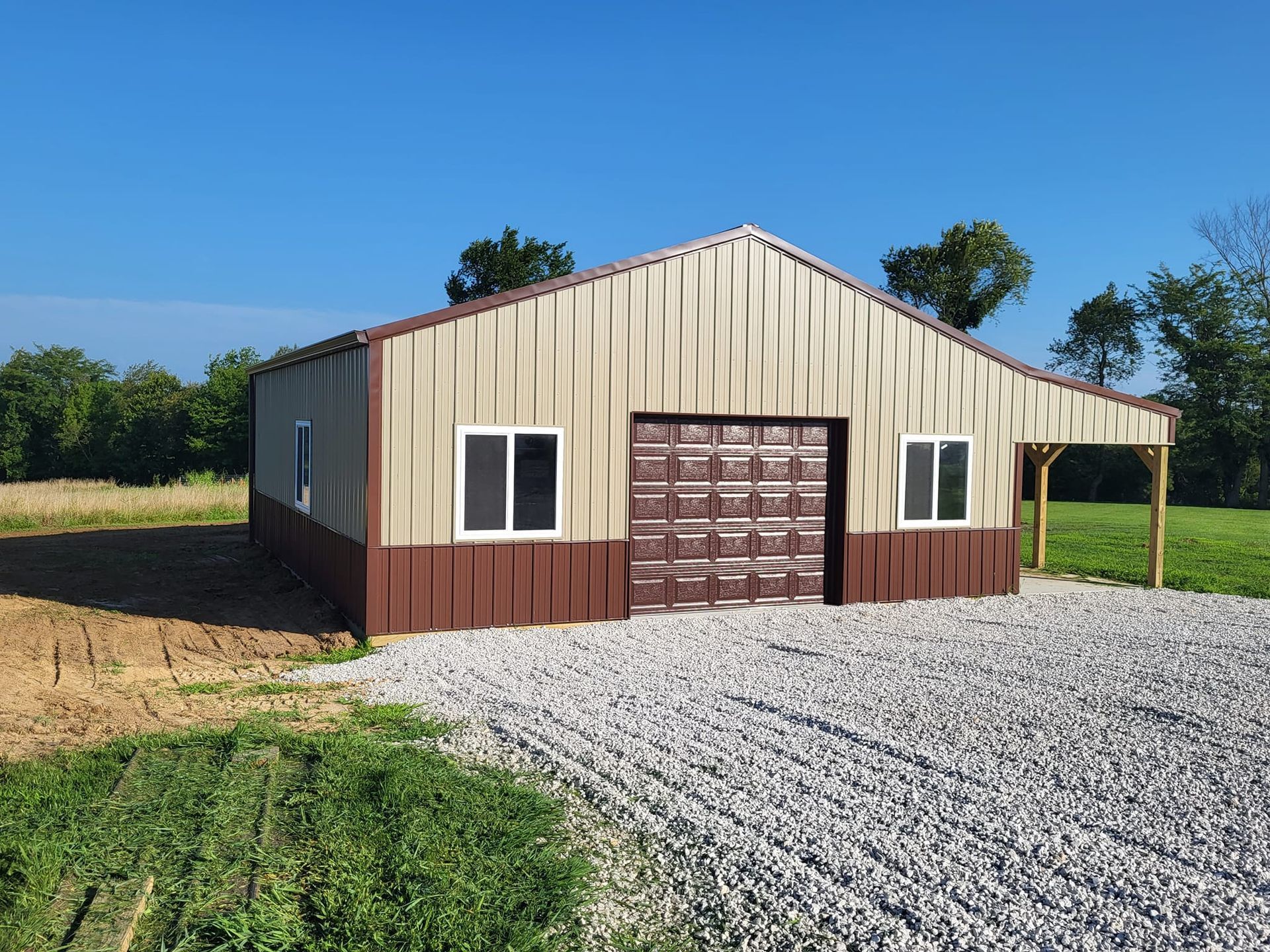 A brown and tan metal building with a garage door and windows.
