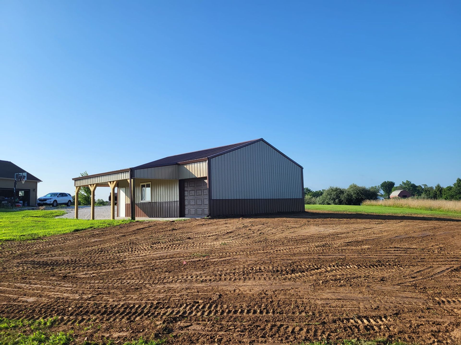 A large barn is sitting in the middle of a dirt field.