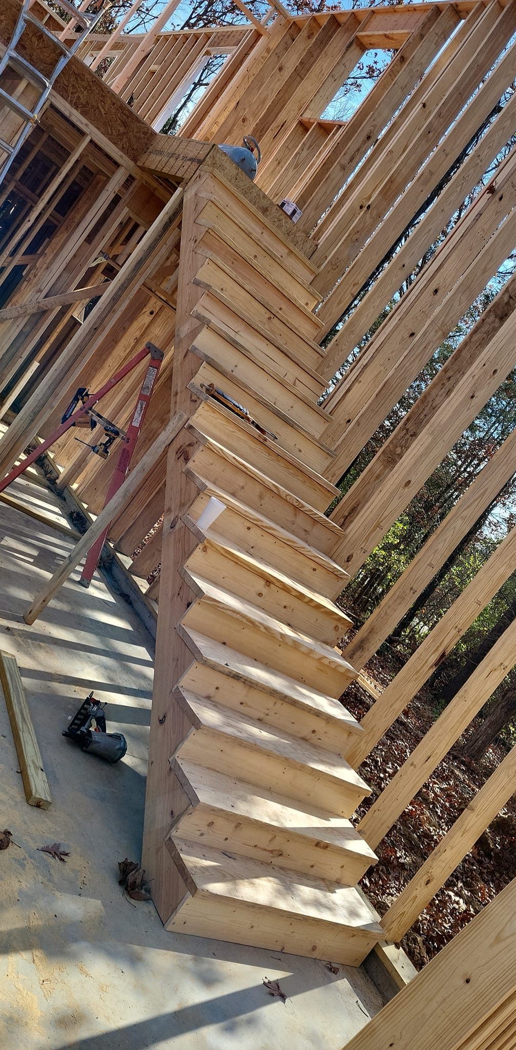 A wooden spiral staircase is being built in a house under construction.