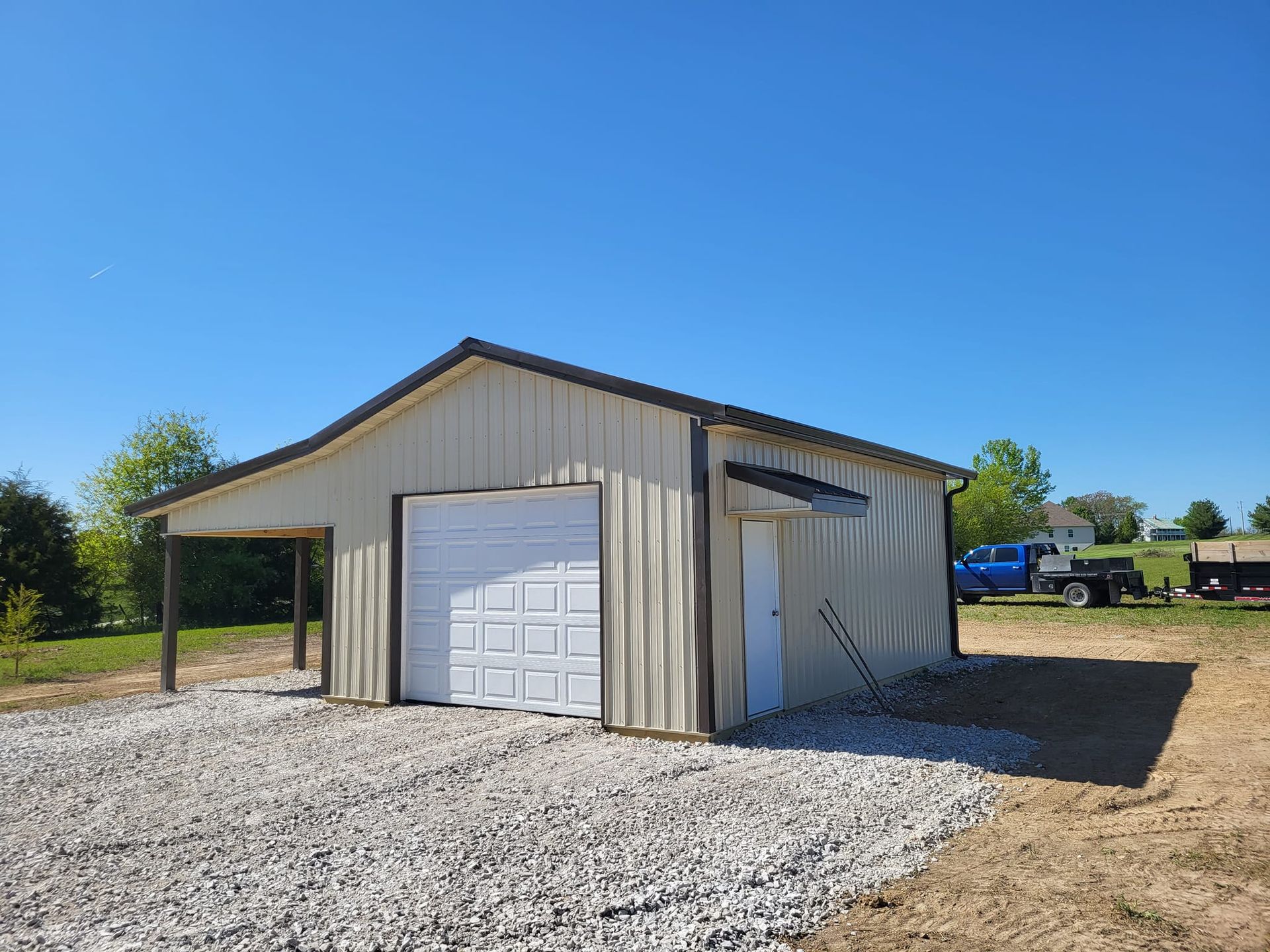 A garage with a white garage door and a blue truck parked in front of it.
