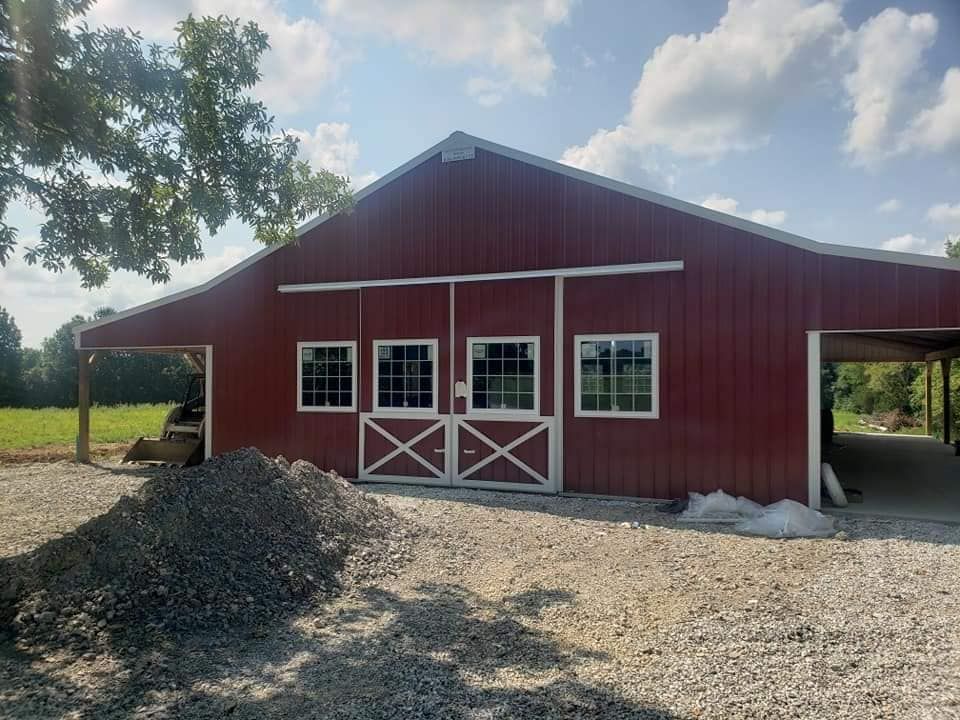 A large red barn with a carport underneath it.