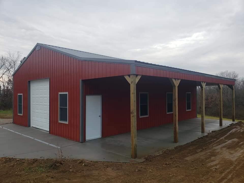 A red metal building with a white garage door and a porch.