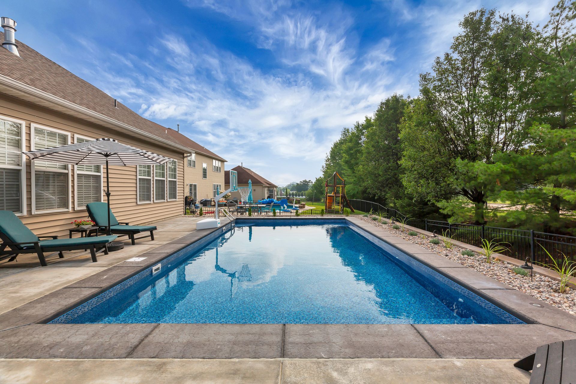 There is a large swimming pool in the backyard of a house.