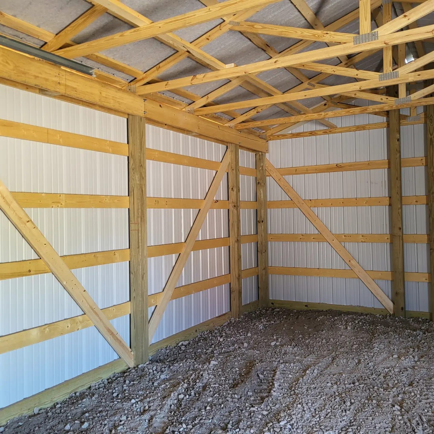 The inside of a building with wooden beams and a gravel floor.
