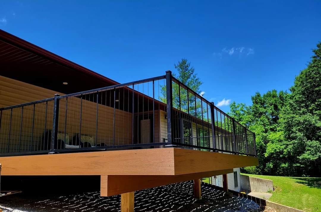 A wooden deck with a metal railing is sitting next to a house.