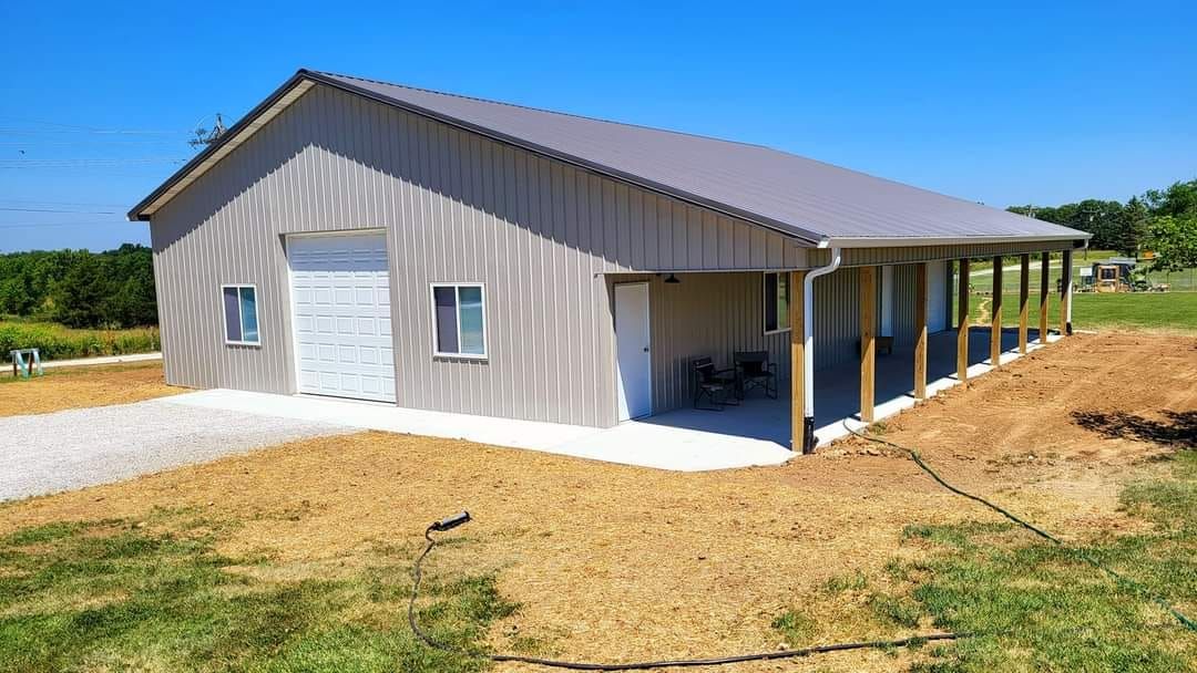 A large metal building with a porch in the middle of a field.