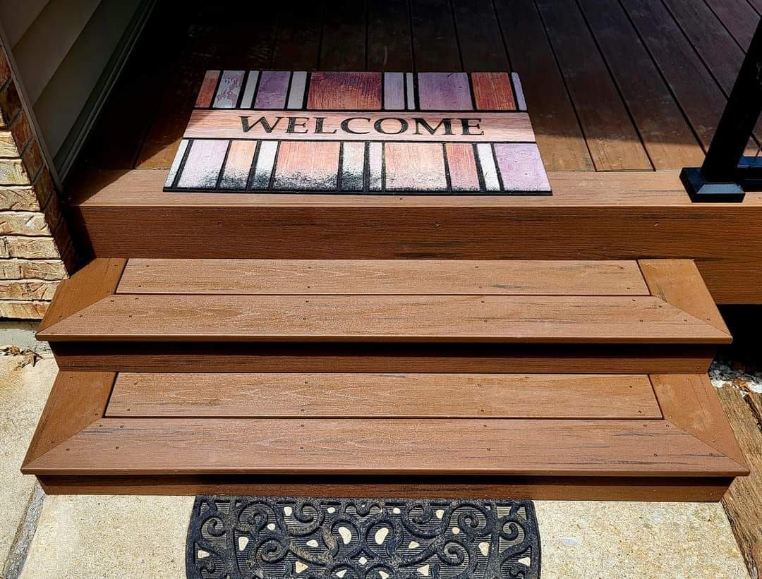 A wooden porch with a welcome mat on the steps.