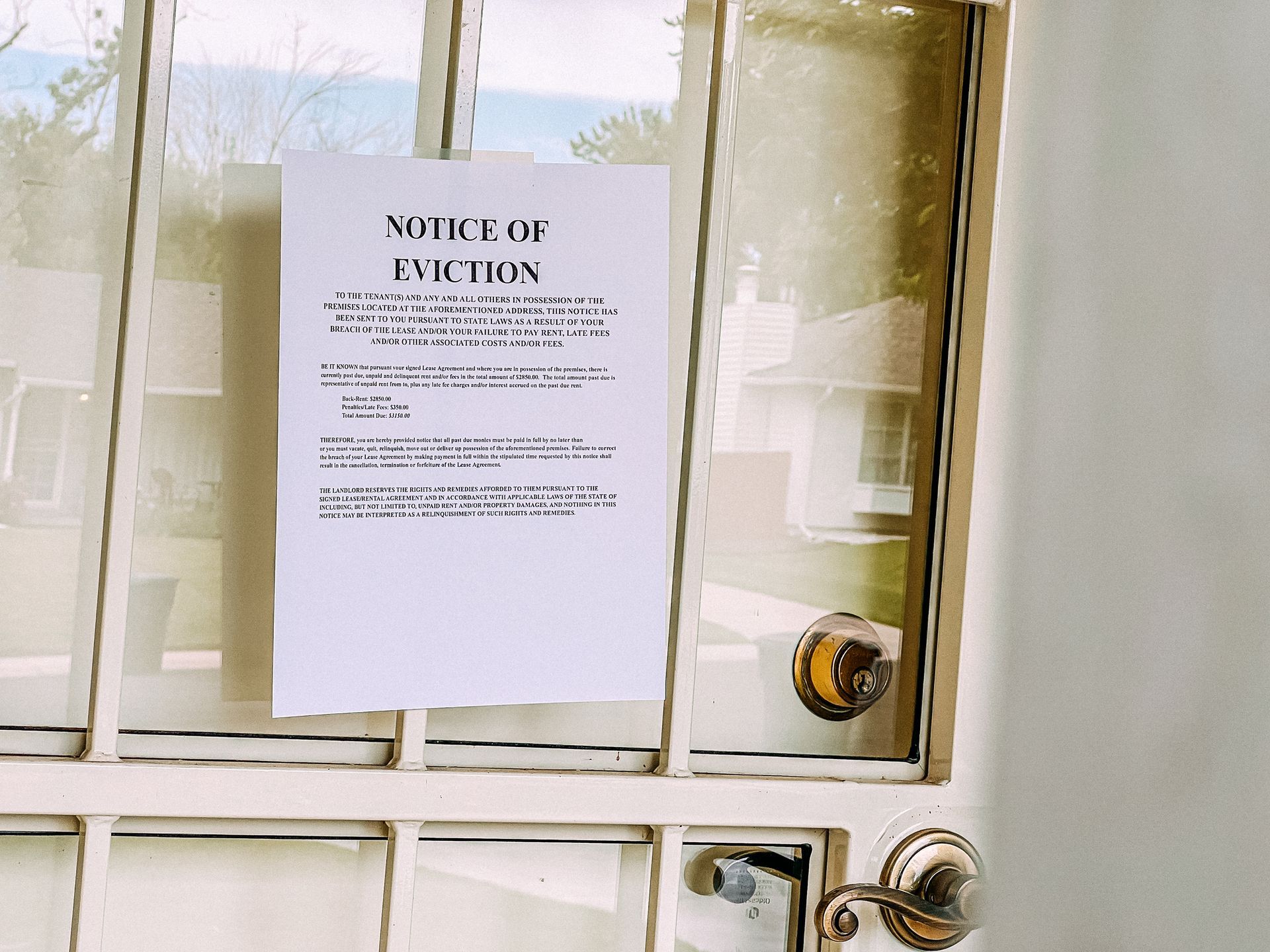 Eviction notice posted on a door warning tenants of legal action for unpaid rent and lease breach.
