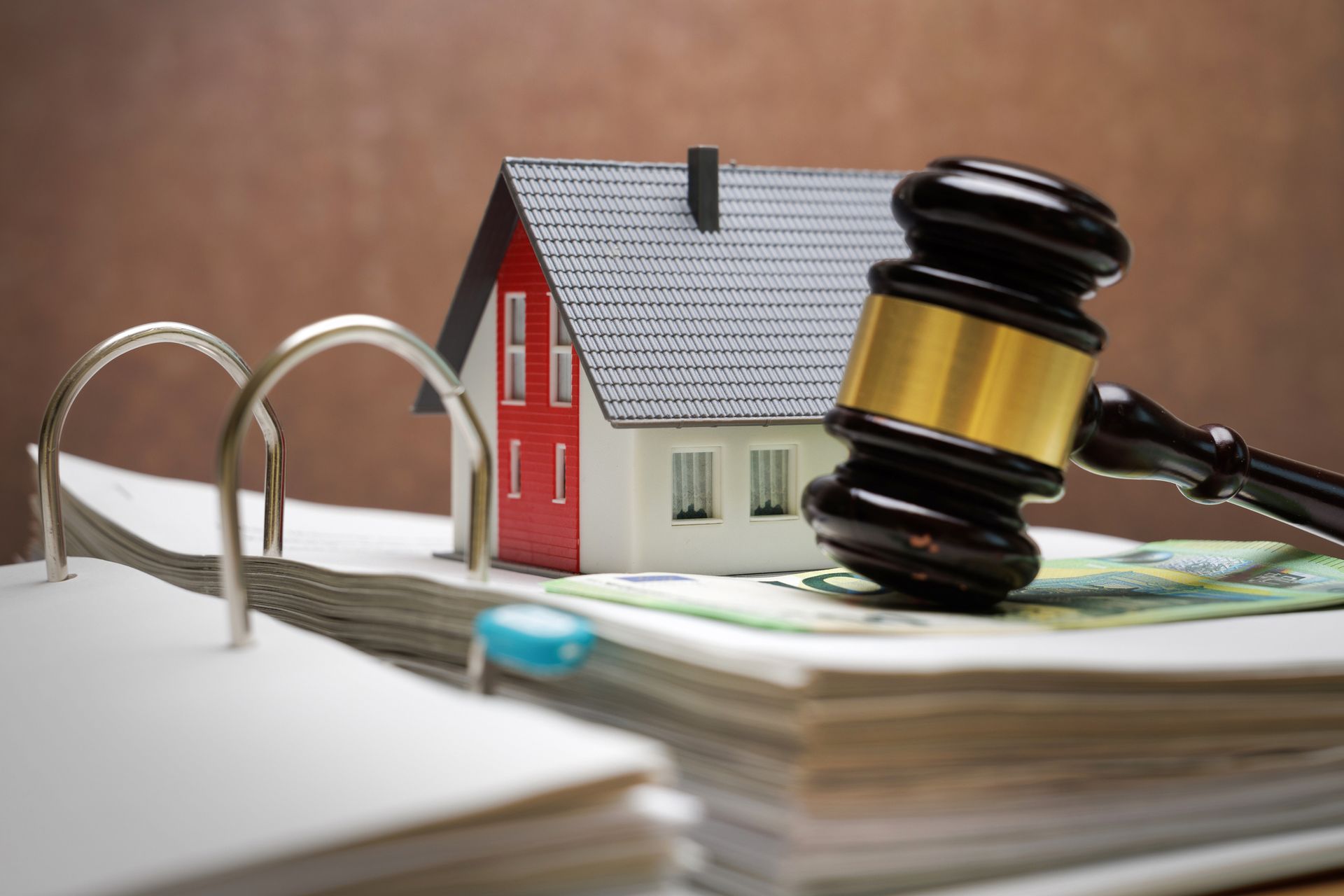 Model house and judge’s gavel on an open binder, symbolizing legal action in housing disputes.
