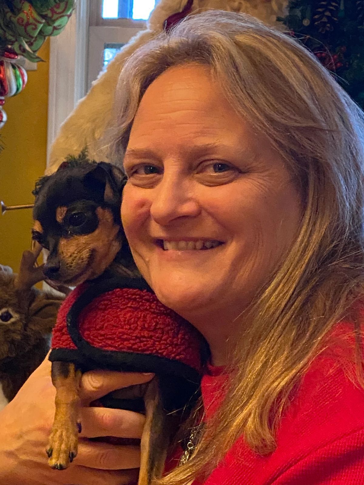 A woman is holding a small dog in her arms.