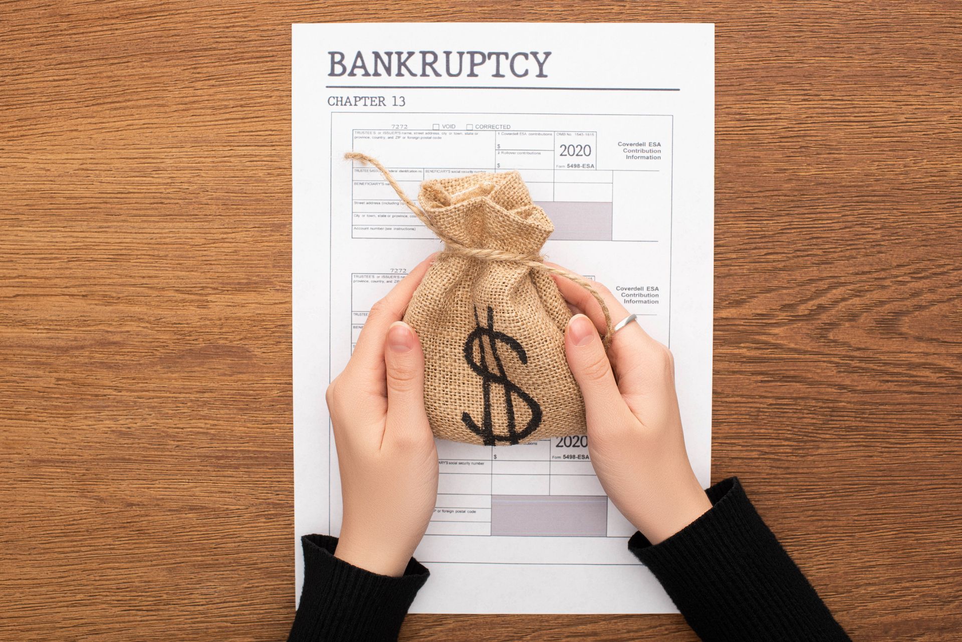 Woman holding a money bag near a Chapter 13 bankruptcy form Woman holding a money bag near a Chapter 13 bankruptcy form