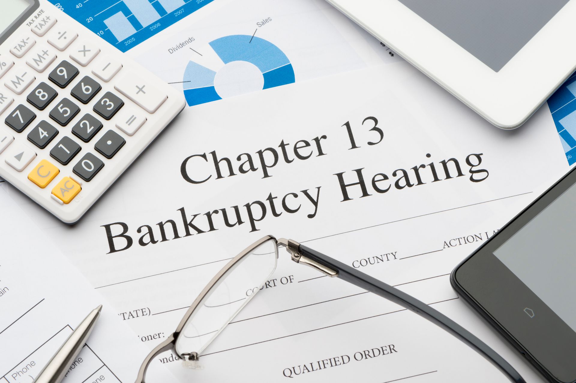 Chapter 13 bankruptcy form, below glasses, and a calculator