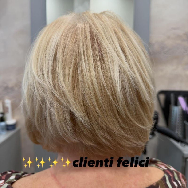 Vista posteriore di un caschetto biondo corto e scalato in un salone di bellezza, con la scritta 