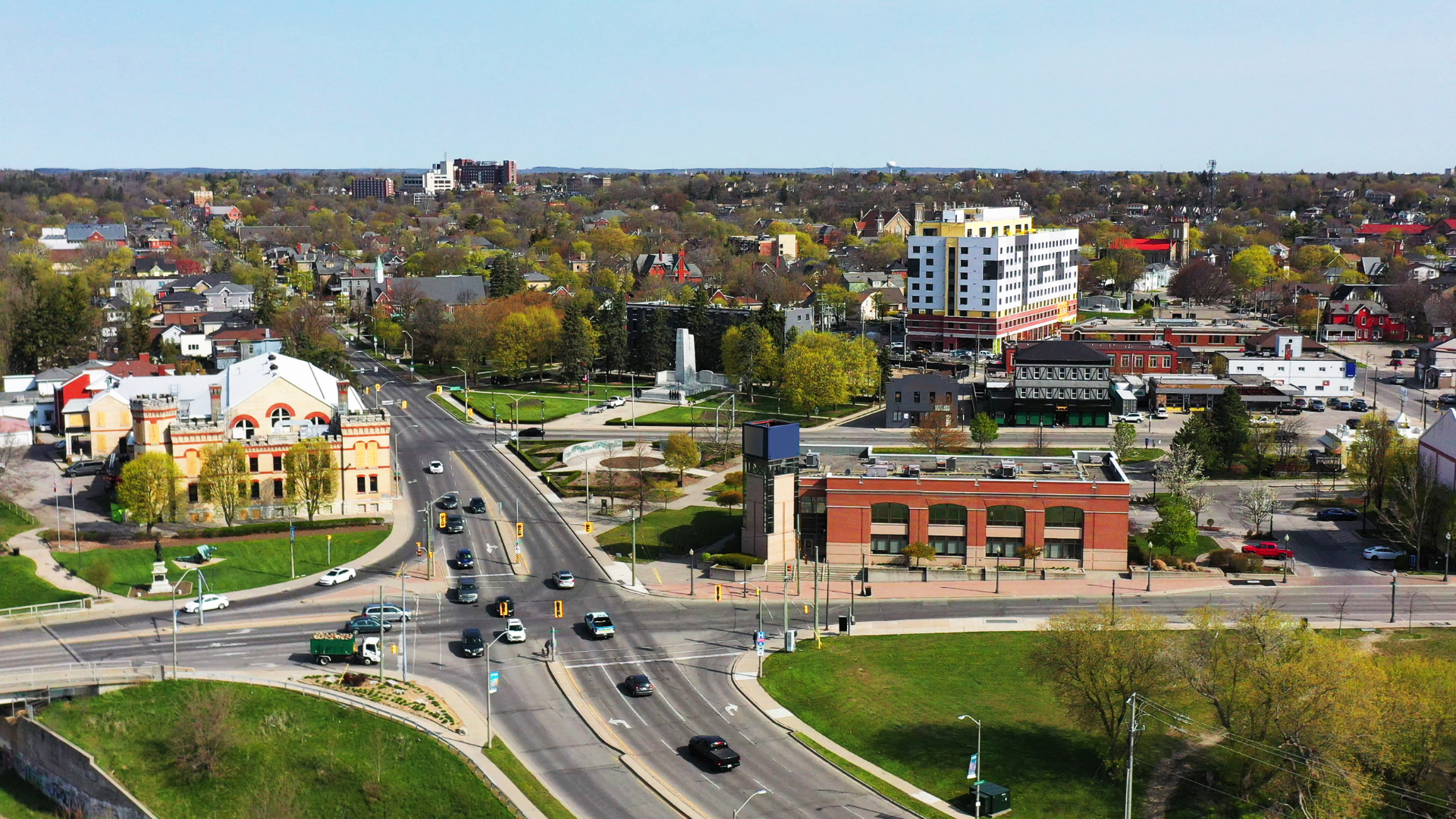 Aerial view of a city intersection with cars and buildings on a sunny day.