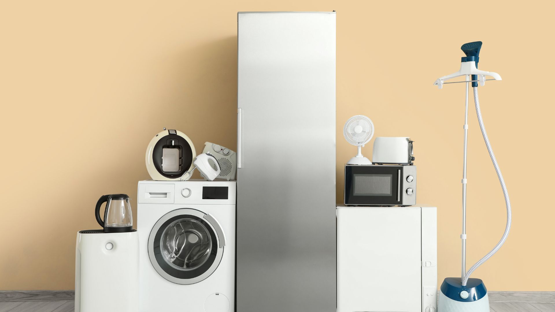 Various white and silver appliances on a light yellow wall: washer, fridge, microwave, steamer, coffee machine.
