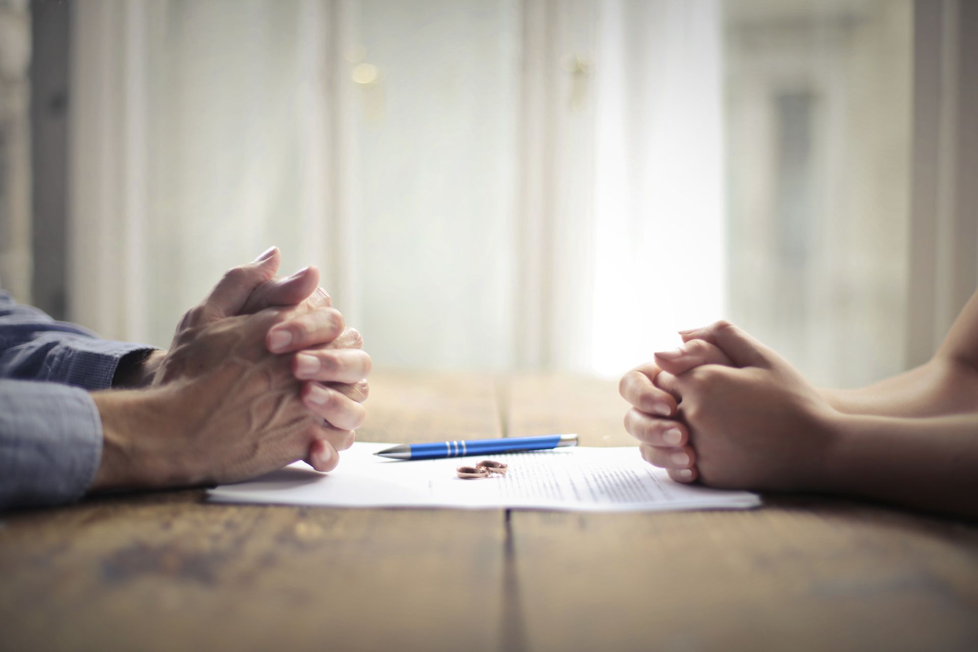Divorce agreement discussion with rings on the document across the table.