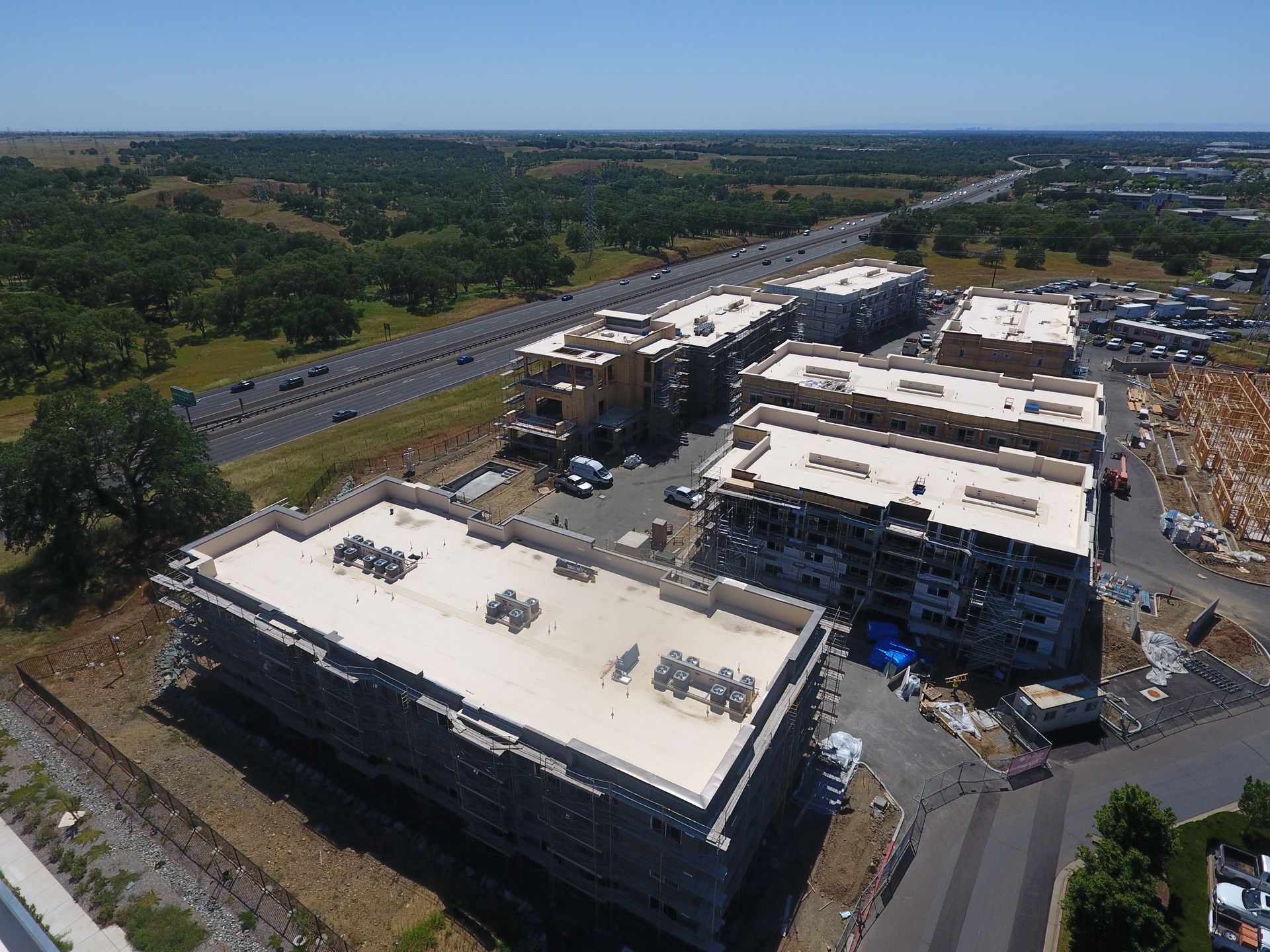 An aerial view of a building under construction with a highway in the background  | Oakland, CA  | Diablo Roofing