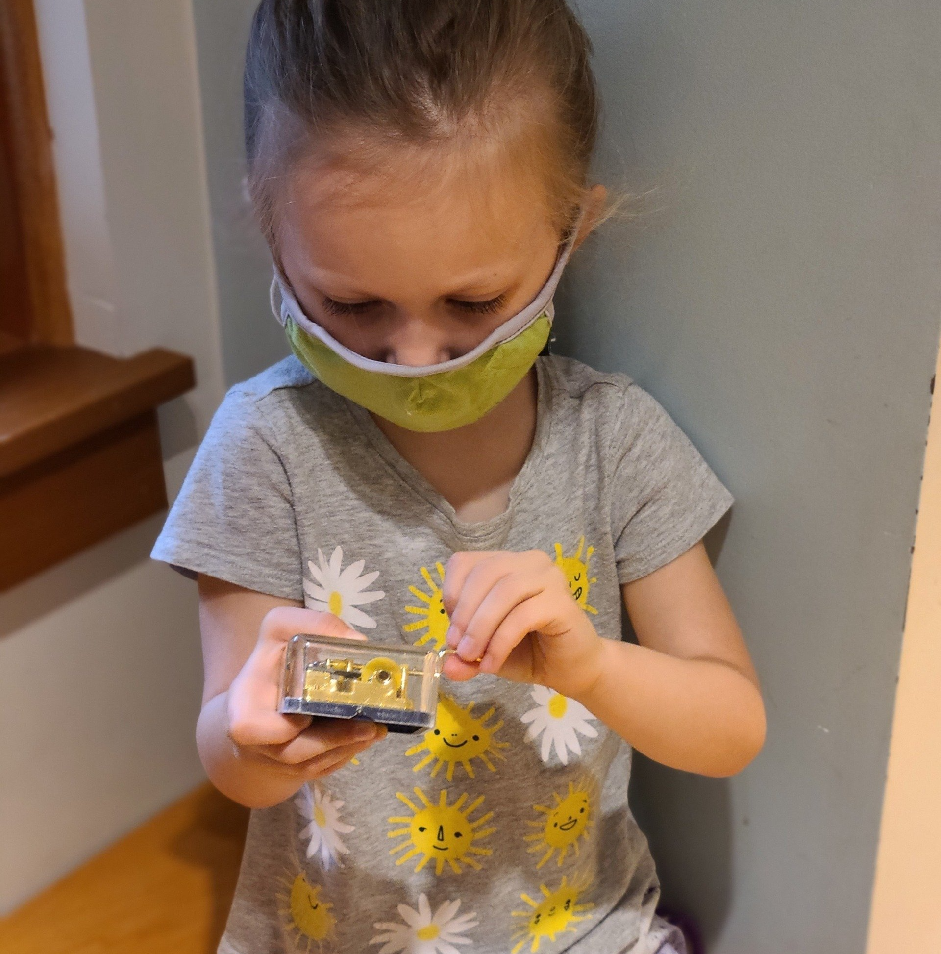 A little primary wearing a mask is playing with a toy