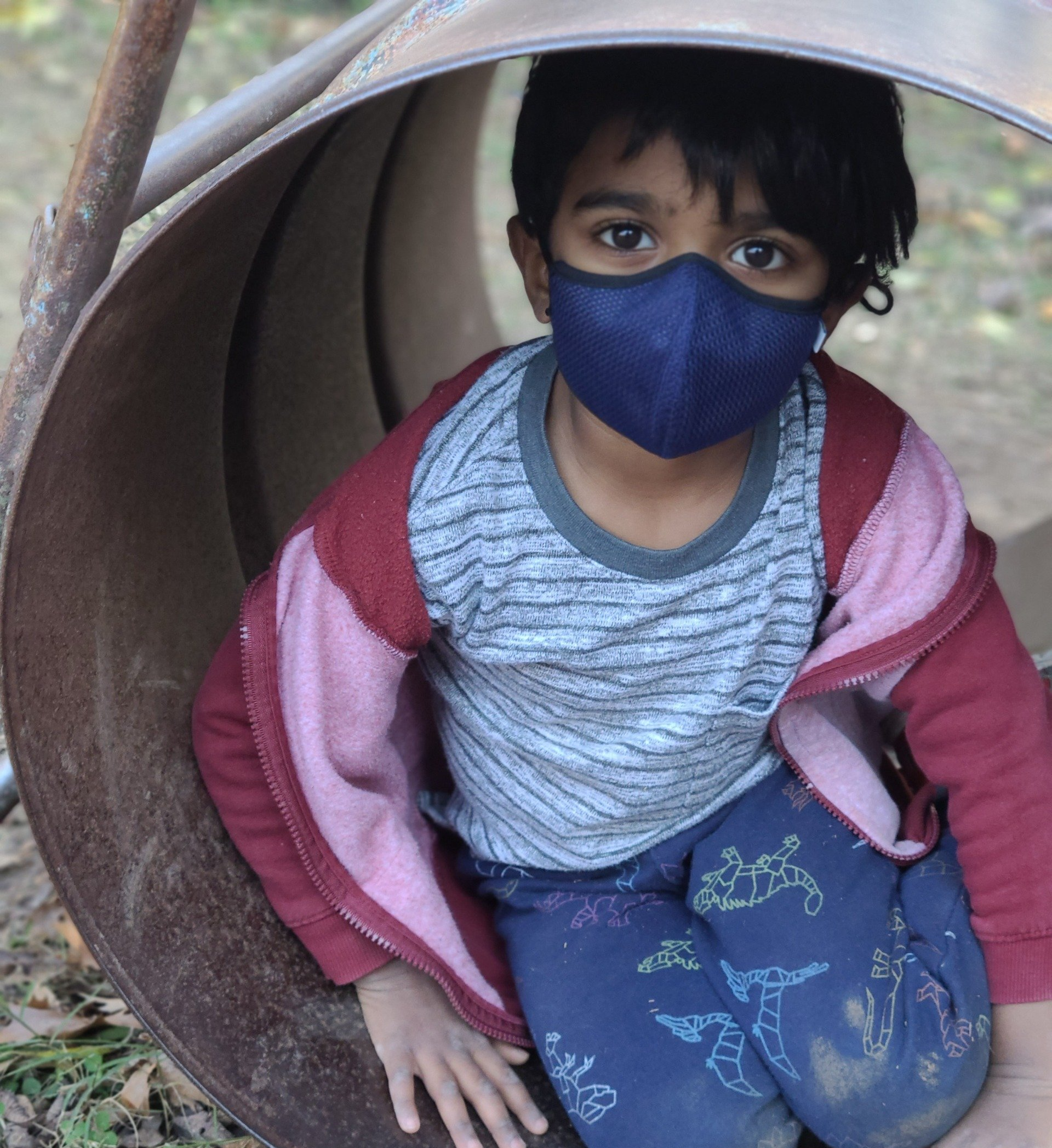 A young boy wearing a mask is sitting in a tunnel