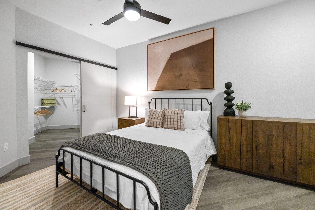 Bedroom with a metal bed frame, gray walls, ceiling fan, and an open closet.