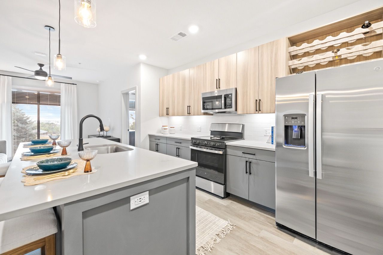 Bright modern kitchen with an island, gray cabinets, and stainless-steel appliances.