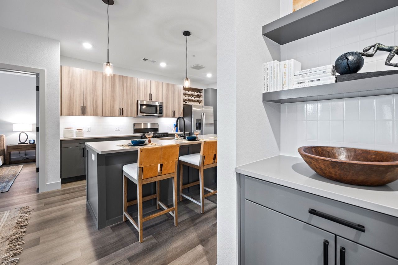 Open-concept kitchen with an island, three bar stools, wood cabinets, and stainless steel appliances.