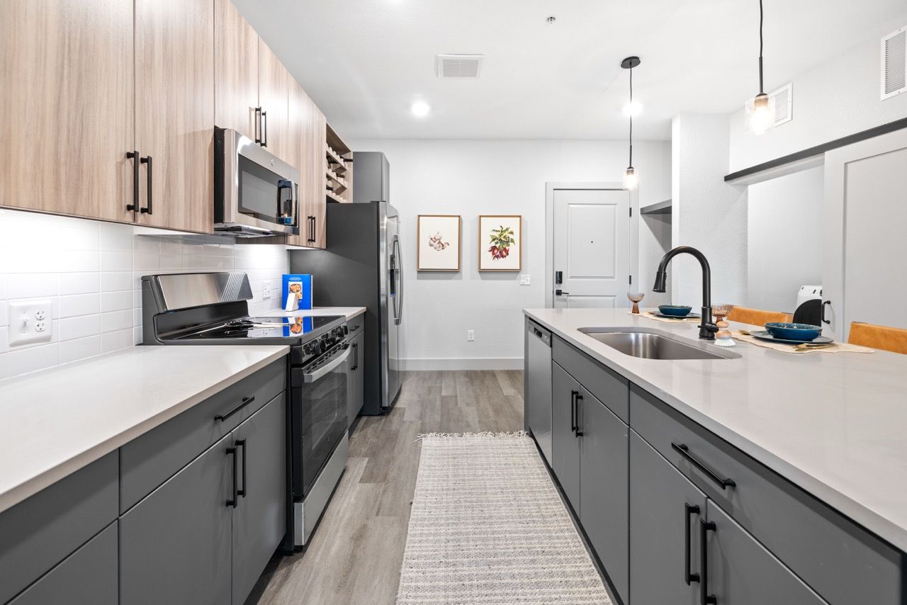 Modern apartment kitchen with gray cabinets, stainless-steel appliances, and an island.