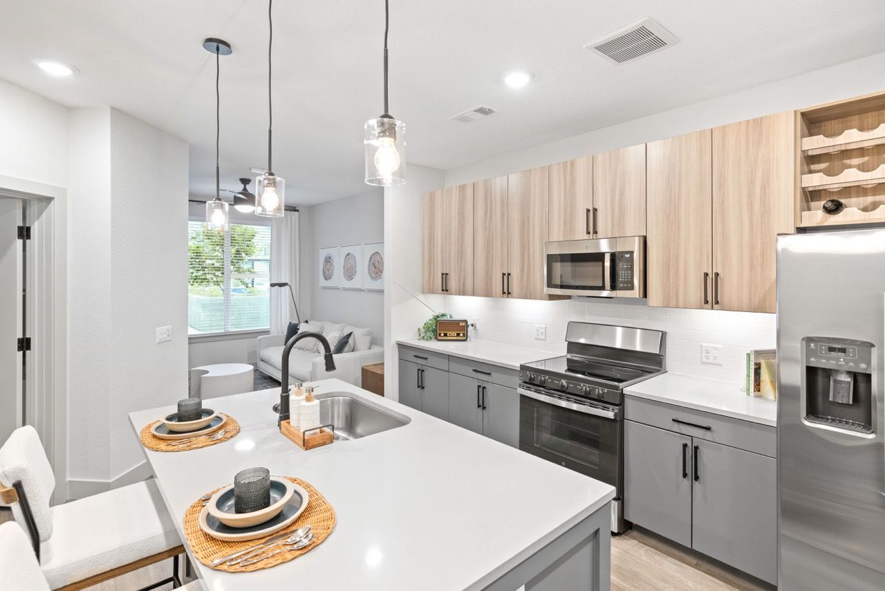 Modern kitchen with island, gray lower cabinets, and stainless steel appliances.