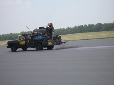 A truck is spraying asphalt on an airport runway
