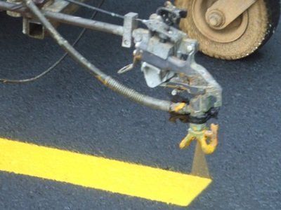 A machine is painting a yellow line on the road
