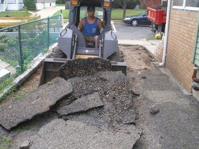 A man in a blue tank top is driving a bulldozer