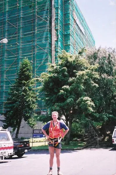 A man is standing in front of a building with scaffolding on it.