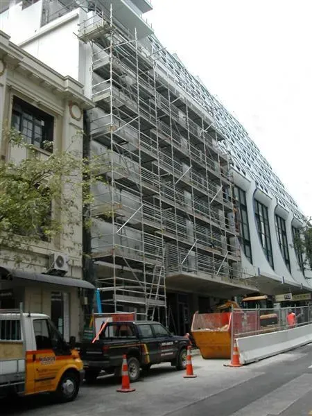 A yellow truck is parked in front of a building under construction