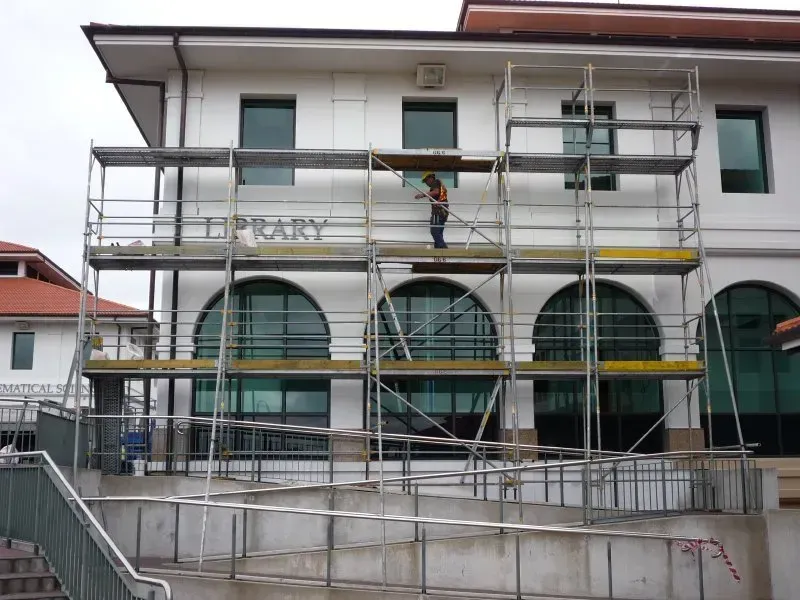 A man is standing on a scaffolding on the side of a building with the word project on it