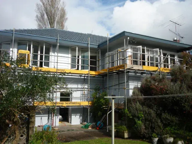 A large house with scaffolding around it is being remodeled.