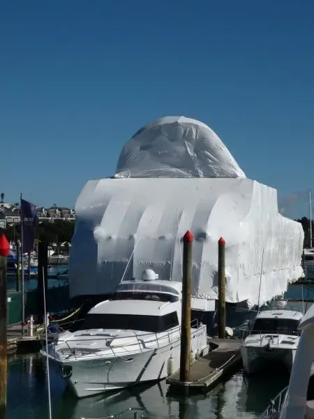 A boat is wrapped in plastic and sitting in the water